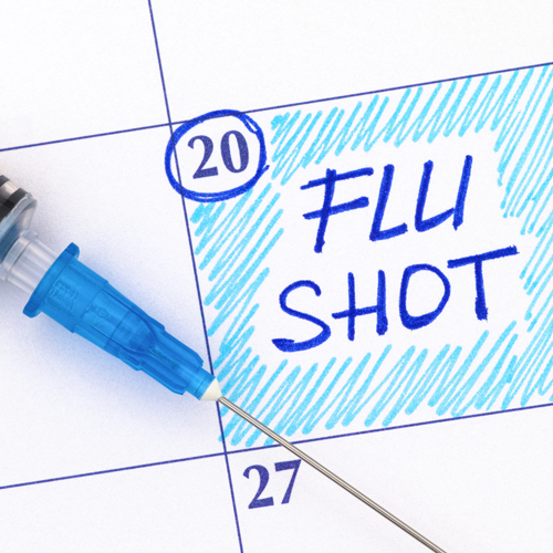 Reminder Flu Shot in calendar with syringe. Close-up.